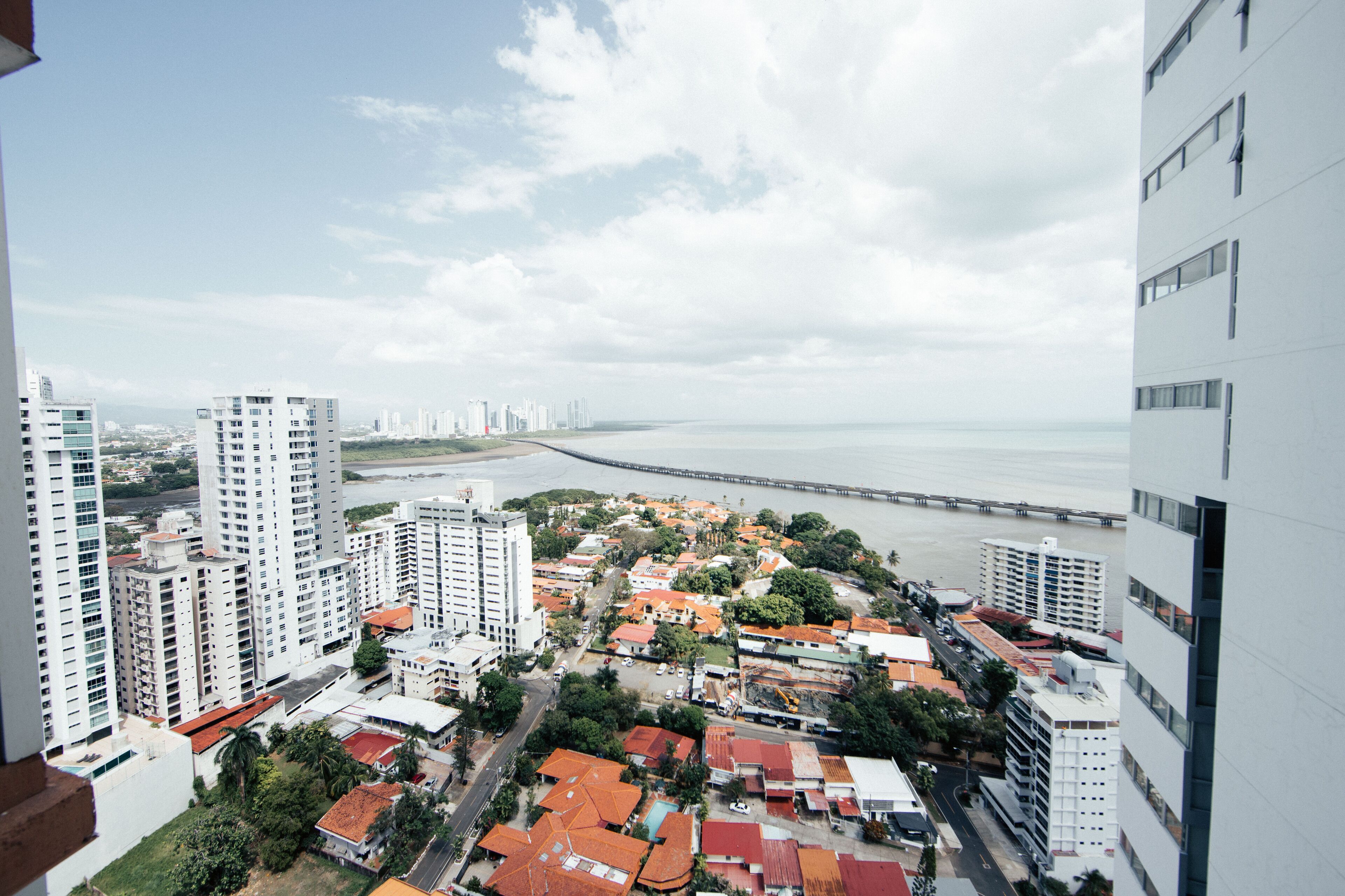 Ein Hochhaus mit Blick auf eine Küstenstadtlandschaft, einen Strand und eine Brücke in der Ferne.