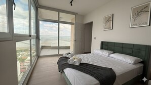 A bedroom with a large bed, a view through a sliding door, and two framed pictures on the wall. - Boutique Apartments Panamá Coco del Mar (Panama City)