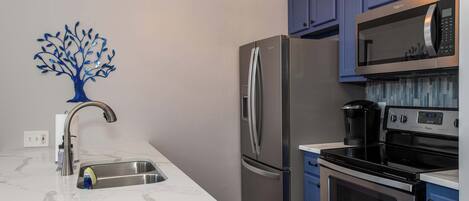 A modern kitchen with a stainless steel refrigerator, a built-in microwave, and an oven.
