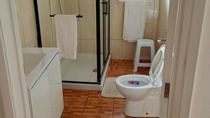 Kylpyhuone, jossa on lasiseinällä varustettu suihku, wc ja pesuallas.