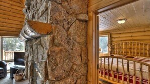 A stone wall with a carved fish, a wooden staircase, and a view of the outdoors. - Beautiful Log Cabin with Acreage (Estes Park)