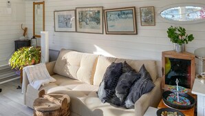 A cozy living room with a beige sofa, a wooden coffee table, and a framed artwork collection on the wall. - Cozy home in Bottnaryd with lake view (Bottnaryd)