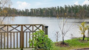 A wooden deck with a view of a lake and trees. - Cozy home in Bottnaryd with lake view (Bottnaryd)