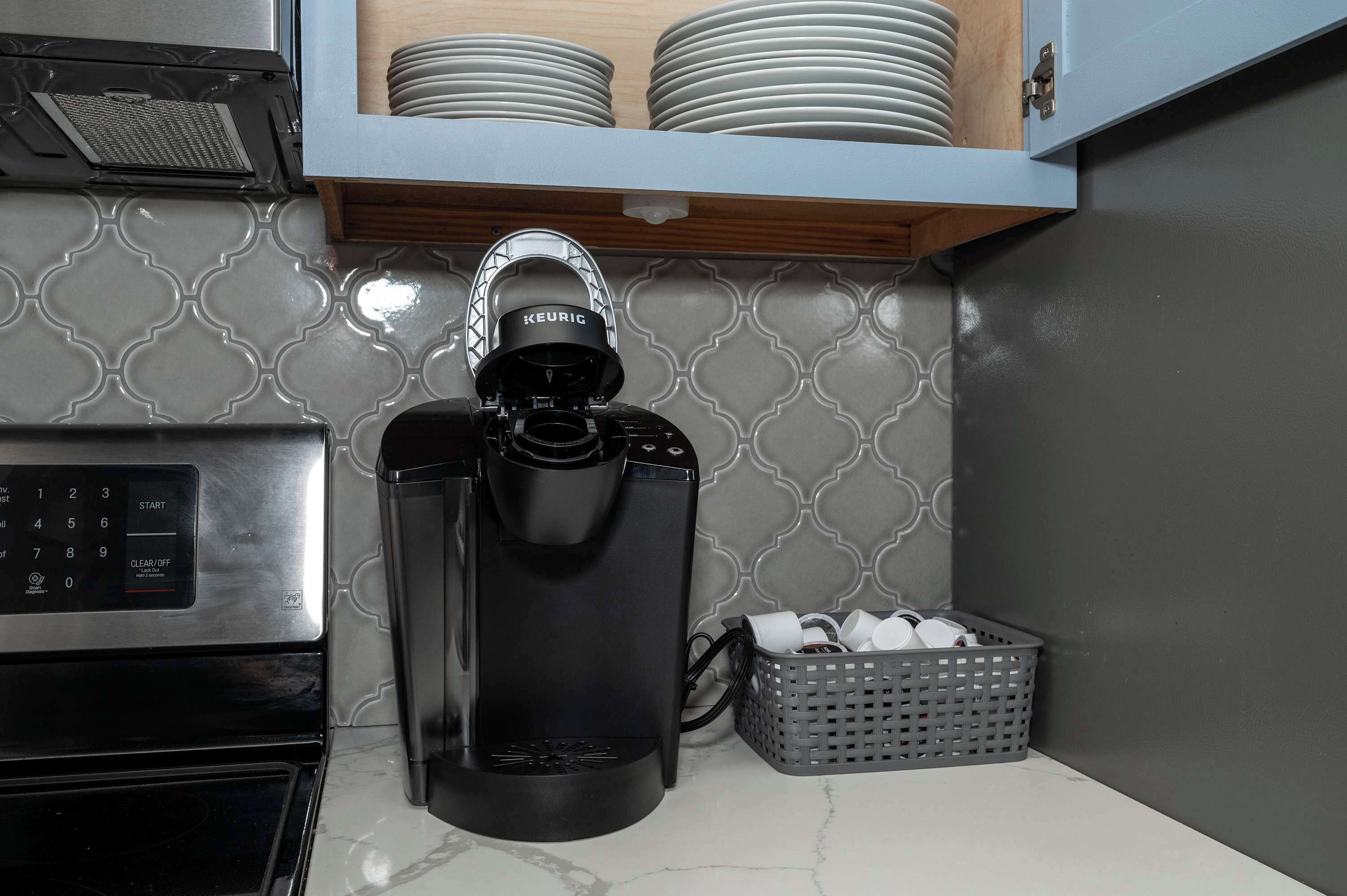 Une machine à café, un panier et une pile d’assiettes dans une cuisine.