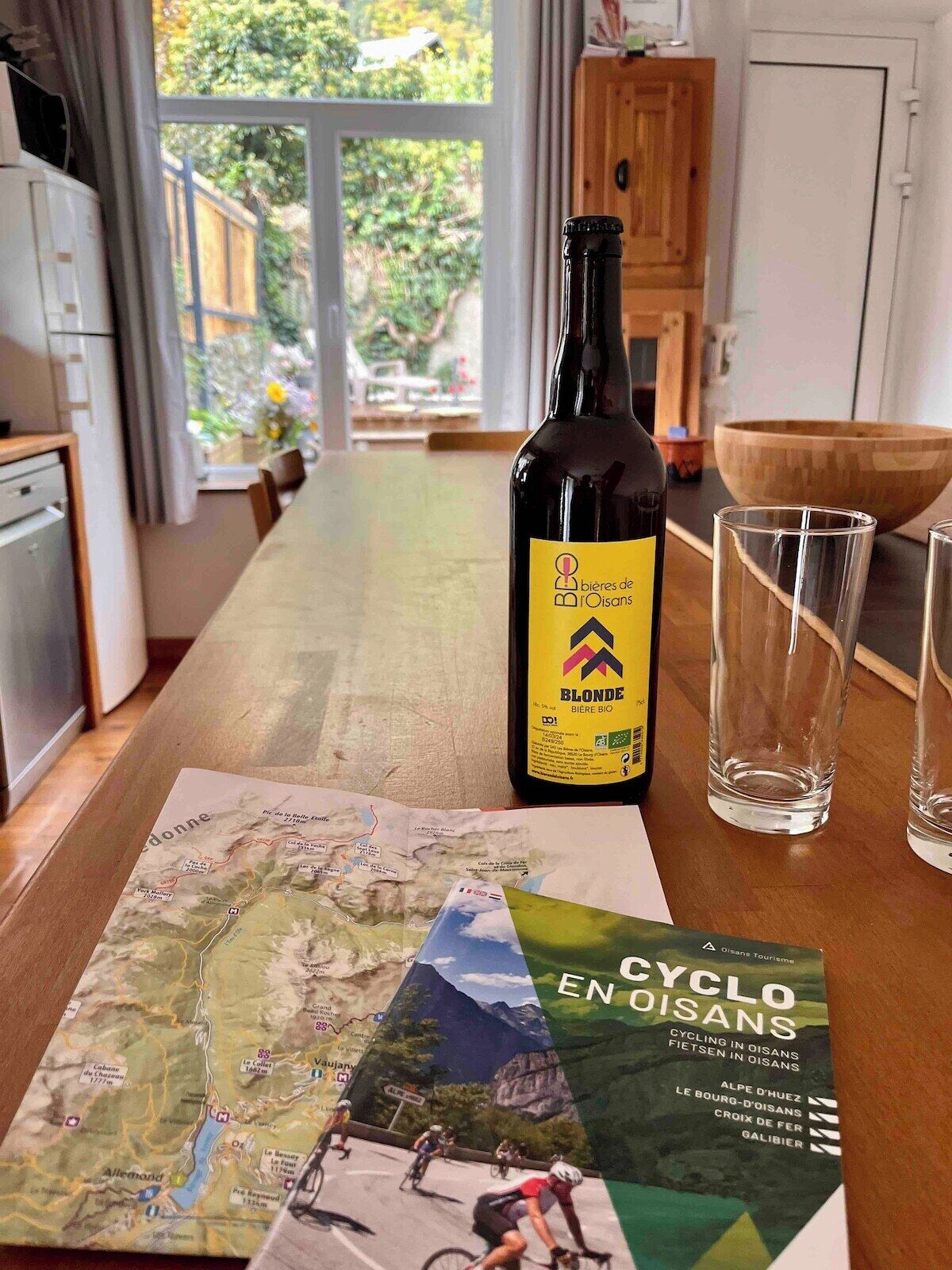 A bottle of Blonde Biere Bio on a table with a cycling map and glasses.