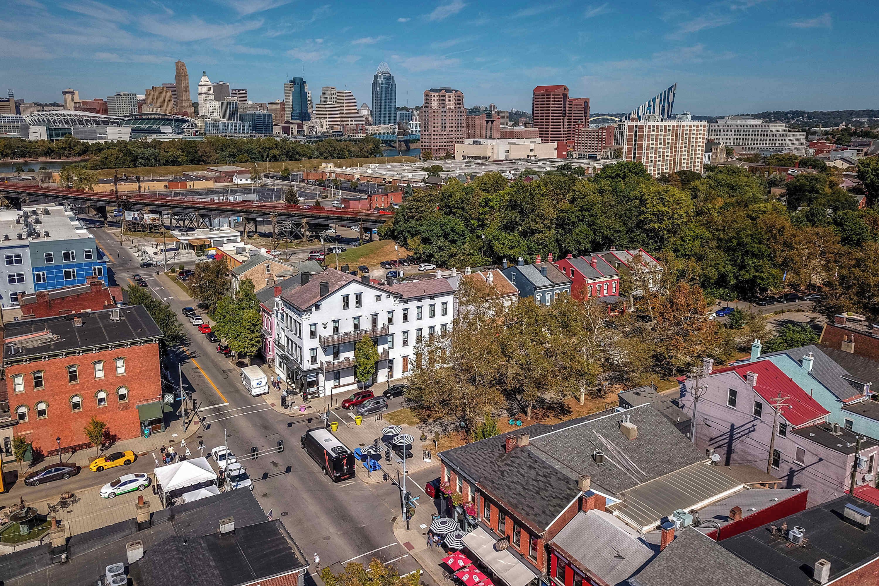 An aerial view of a cityscape with a mix of modern and historic buildings, a prominent stadium, and a river.
