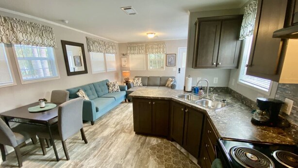 Una cocina moderna con una isla central, muebles oscuros y una zona de comedor con mesa y sillas.
