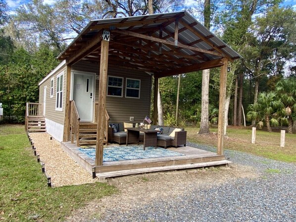 Uma pequena cabana com varanda, área de estar externa e uma bandeira.