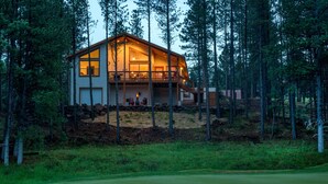 Una casa de dos pisos con un balcón, rodeada de un bosque.
