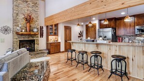Una cocina amplia con chimenea de piedra, taburetes de madera y electrodomésticos modernos.