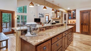 Una cocina amplia con una isla grande, armarios de madera e iluminación colgante.