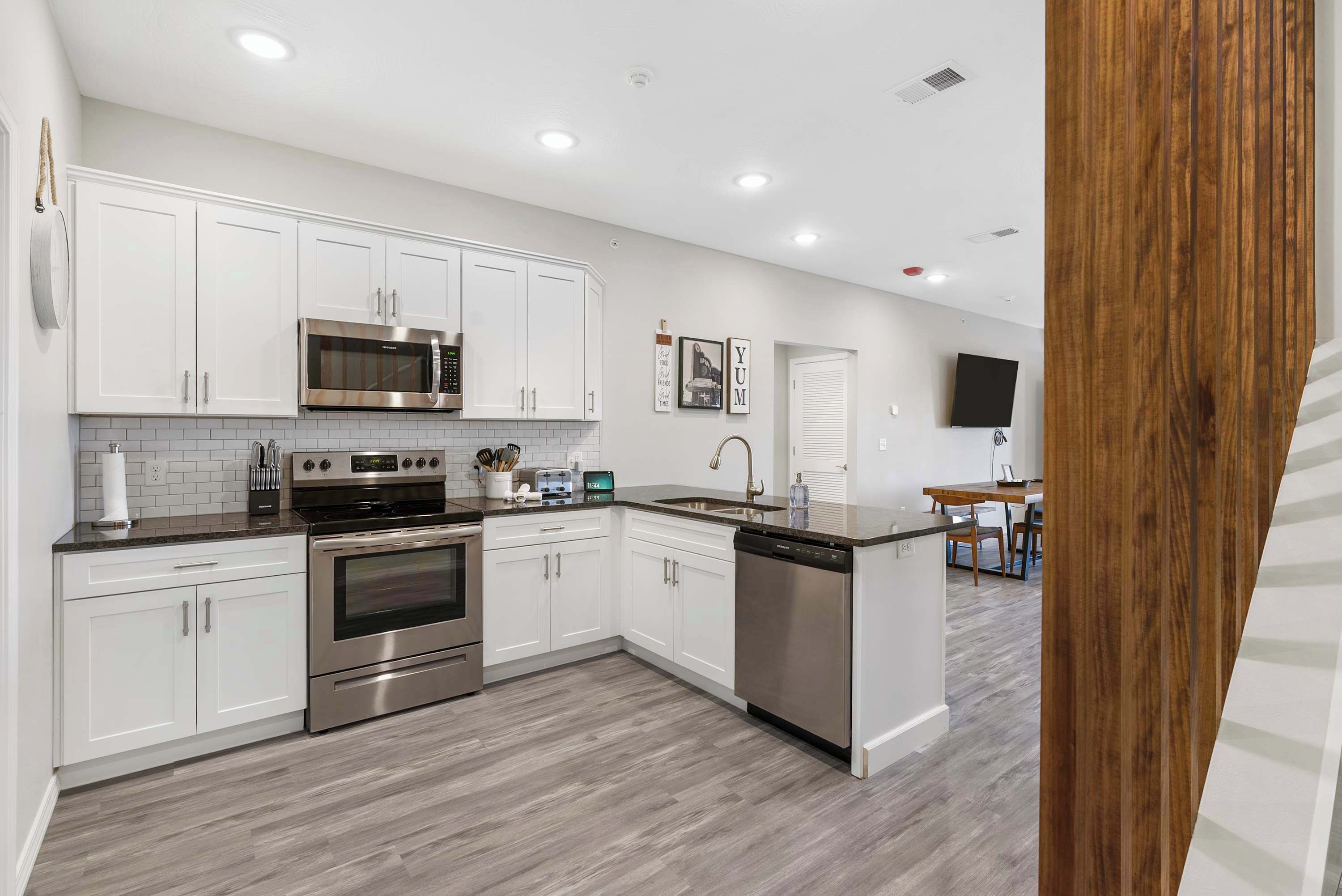 A modern kitchen with white cabinets, stainless steel appliances, and a grey tiled backsplash.