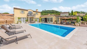 A two-story building with a swimming pool, outdoor seating, and a covered patio area. - Luxurious home in Grimaud (Grimaud)