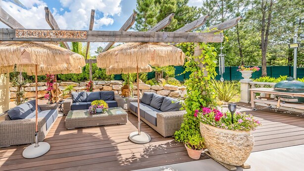 An outdoor patio with wicker furniture, thatched umbrellas, and potted plants. - Luxurious home in Grimaud (Grimaud)