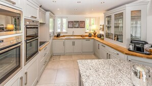 A modern kitchen with stainless steel appliances, a granite countertop, and a large window providing natural light. - Luxurious home in Grimaud (Grimaud)