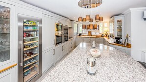 A modern kitchen with a granite countertop, stainless steel appliances, and a central island with a glass top. - Luxurious home in Grimaud (Grimaud)