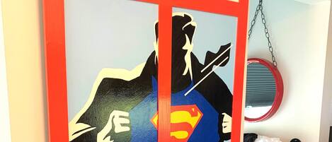 Una pared con un letrero de teléfono rojo y la silueta de Superman.