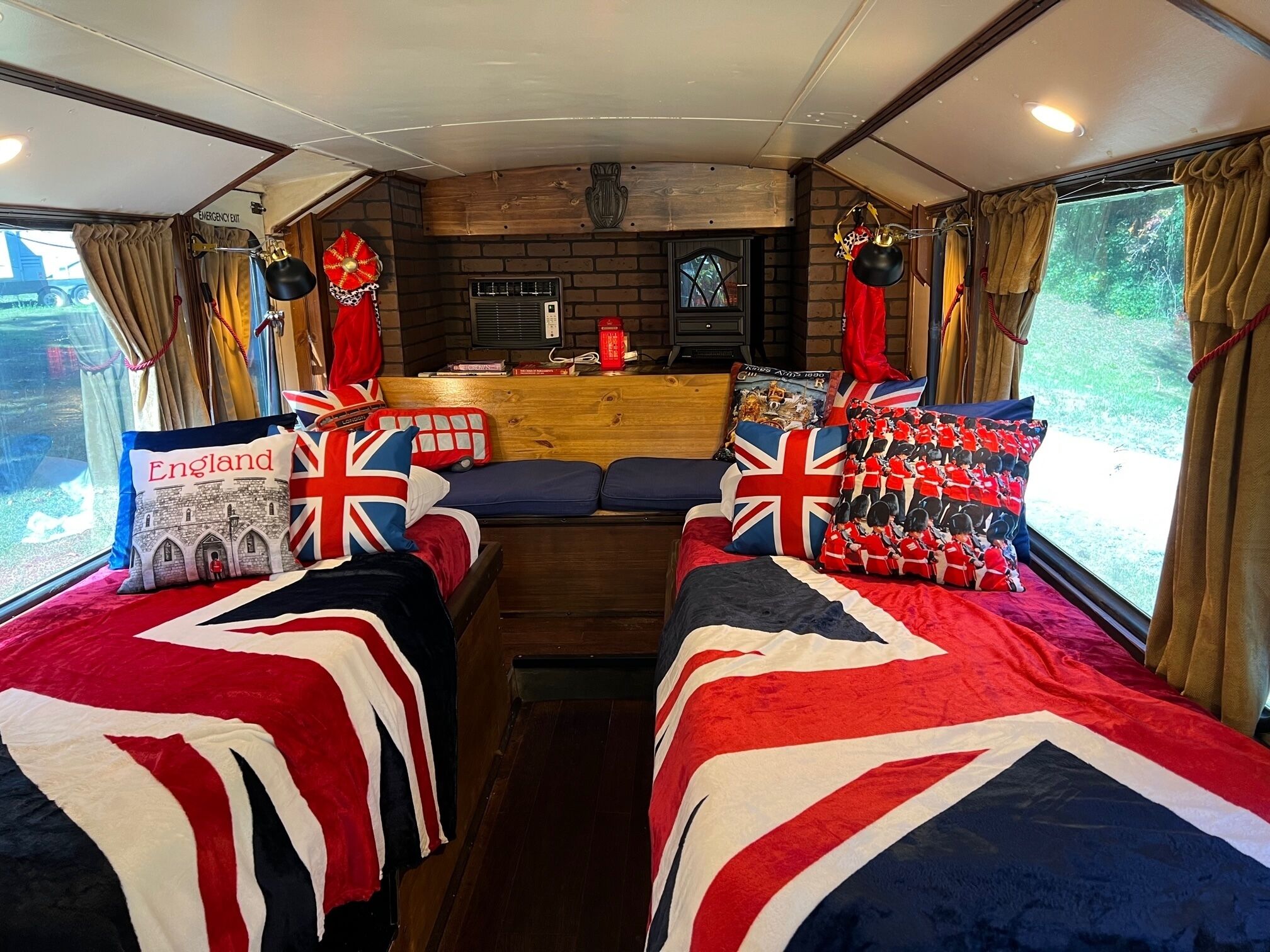 Un interior acogedor con dos camas decoradas con banderas británicas, un banco de madera y una pequeña mesa con un farol rojo.