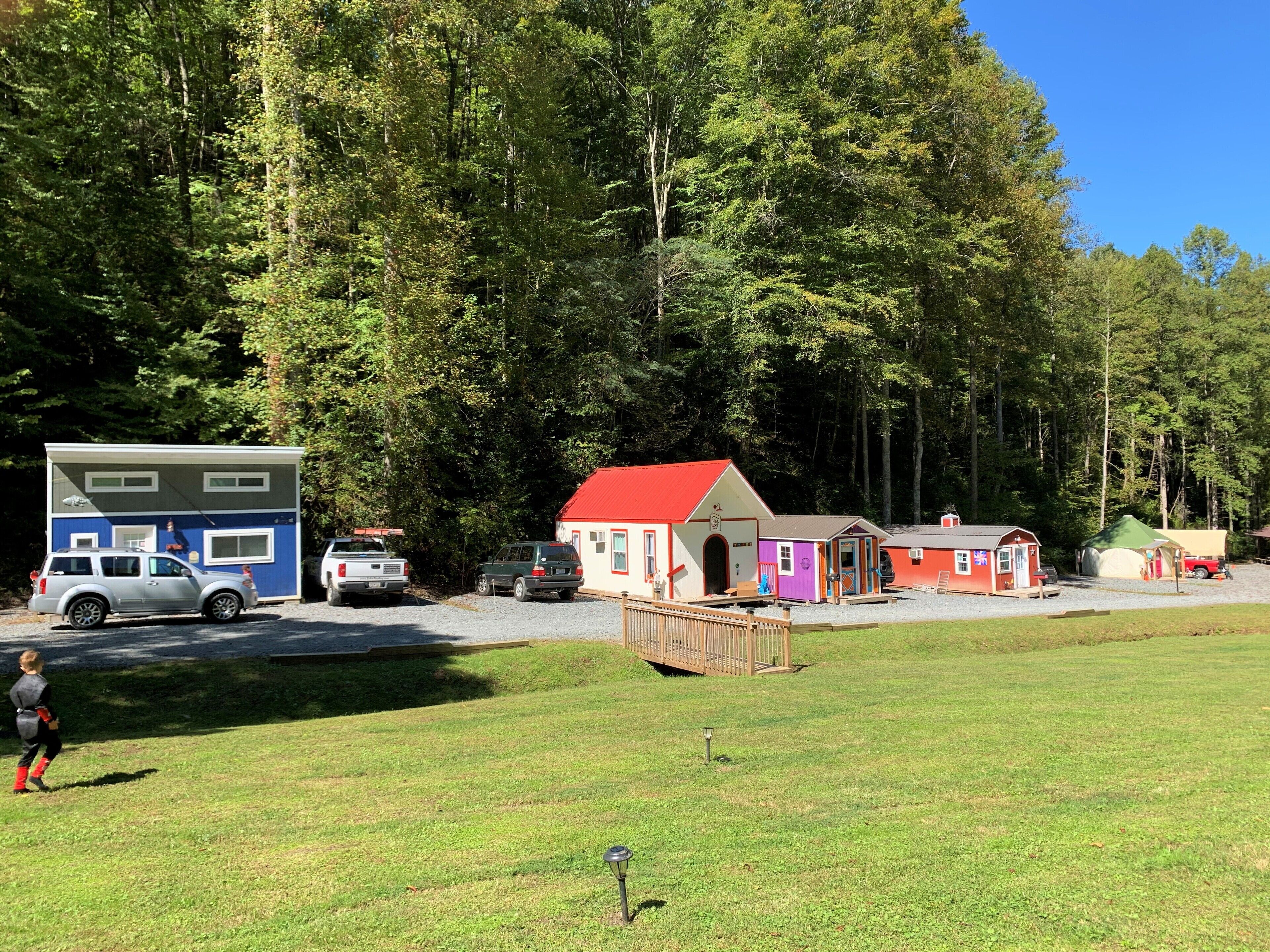 A campground with RVs, a large blue building, and several colorful cabins.