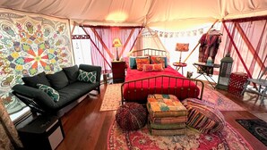 A tented accommodation with a bed, a sofa, and a patterned wall.