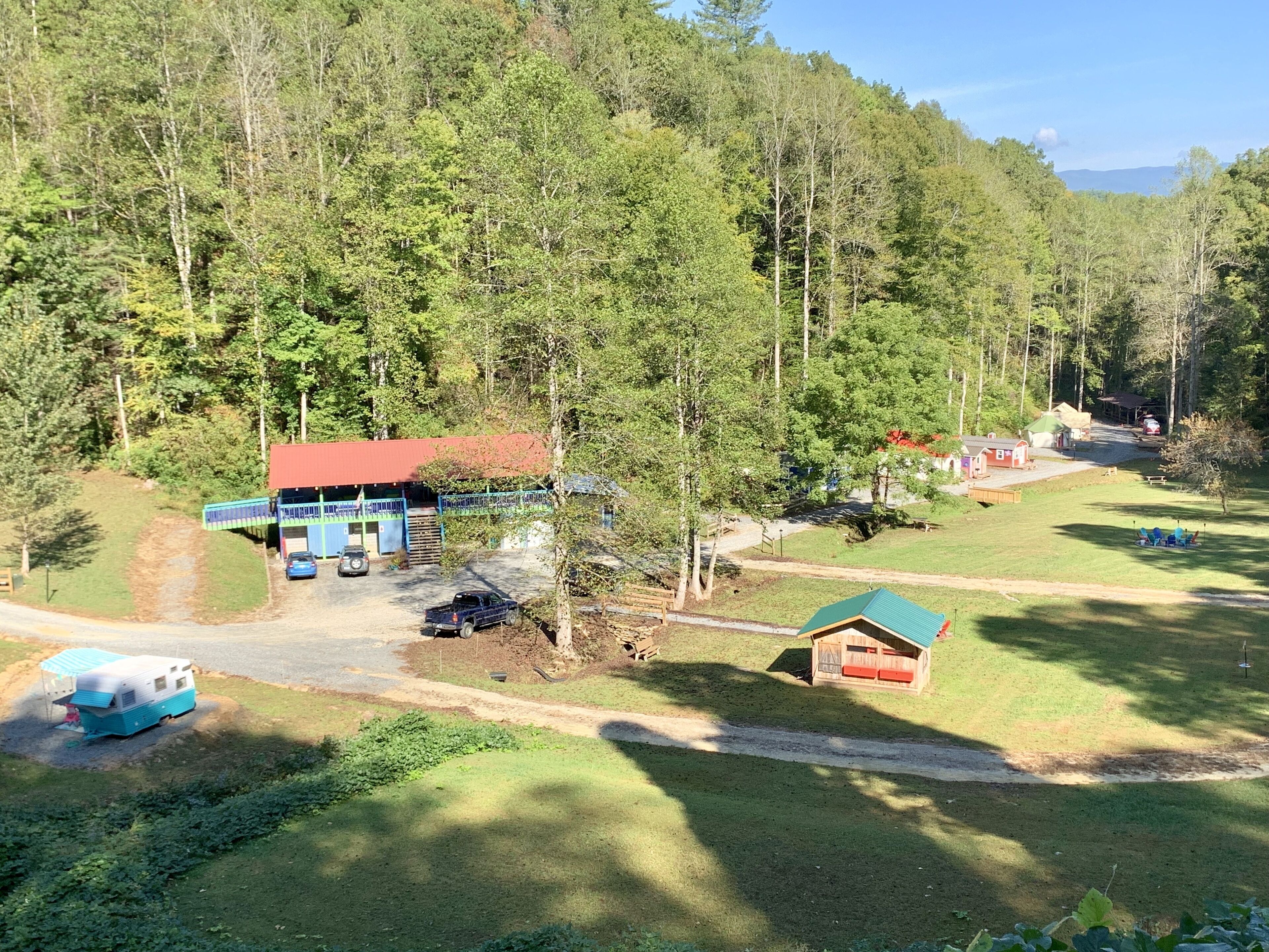 A rural property with a main building, a small cabin, and a blue caravan.