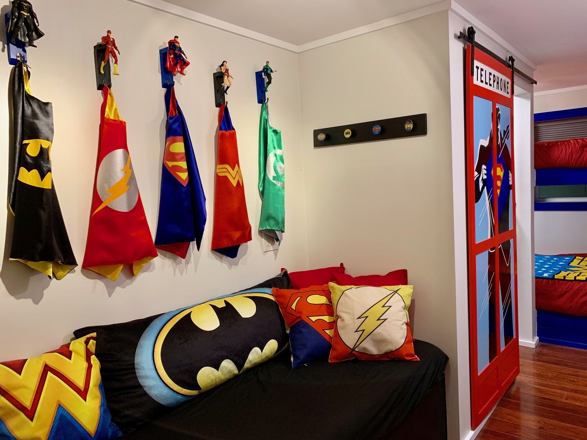 Una camera da letto con decorazioni a tema supereroi, tra cui bandiere e cuscini.