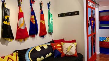 Una camera da letto con decorazioni a tema supereroi, tra cui bandiere e cuscini.