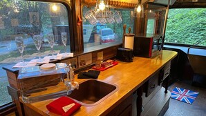 A compact kitchen with a wooden counter, a sink, and a window overlooking a garden.