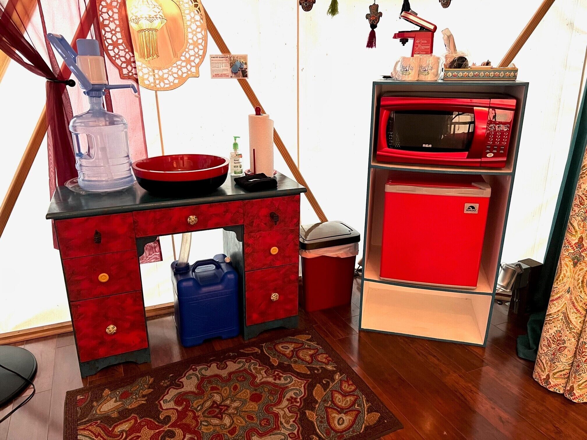 Una kitchenette compacta con un refrigerador rojo, un microondas, un lavamanos y una pequeña encimera.