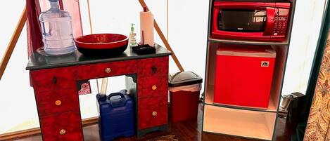 Una kitchenette compacta con un refrigerador rojo, un microondas, un lavamanos y una pequeña encimera.