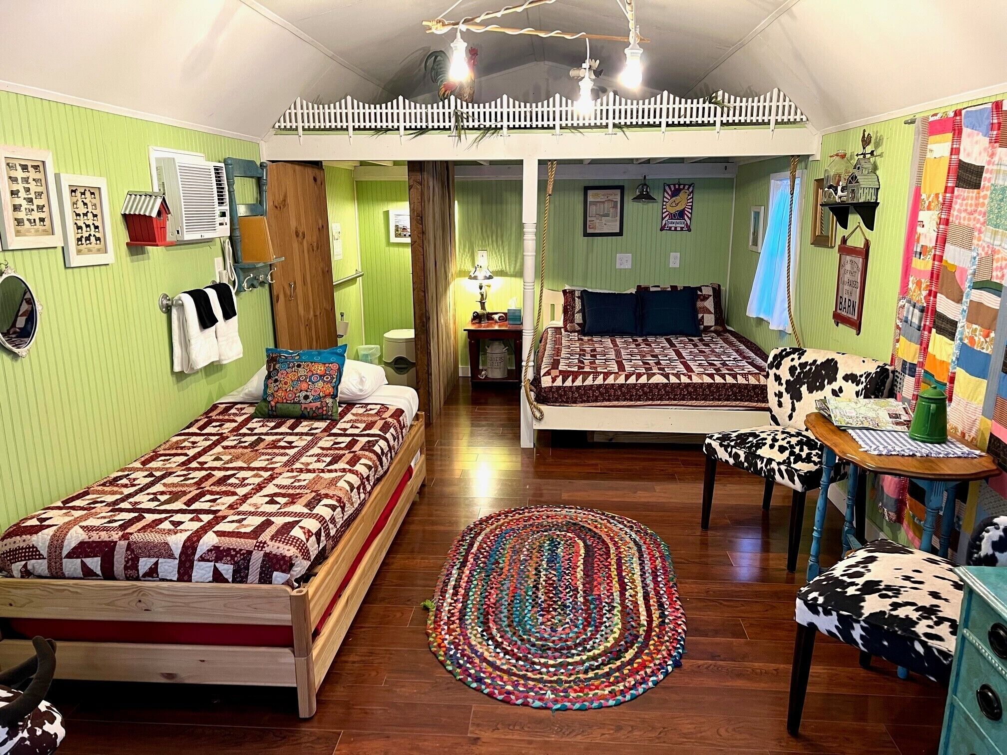 A cozy room with two beds, a colorful rug, and a cow-print chair.