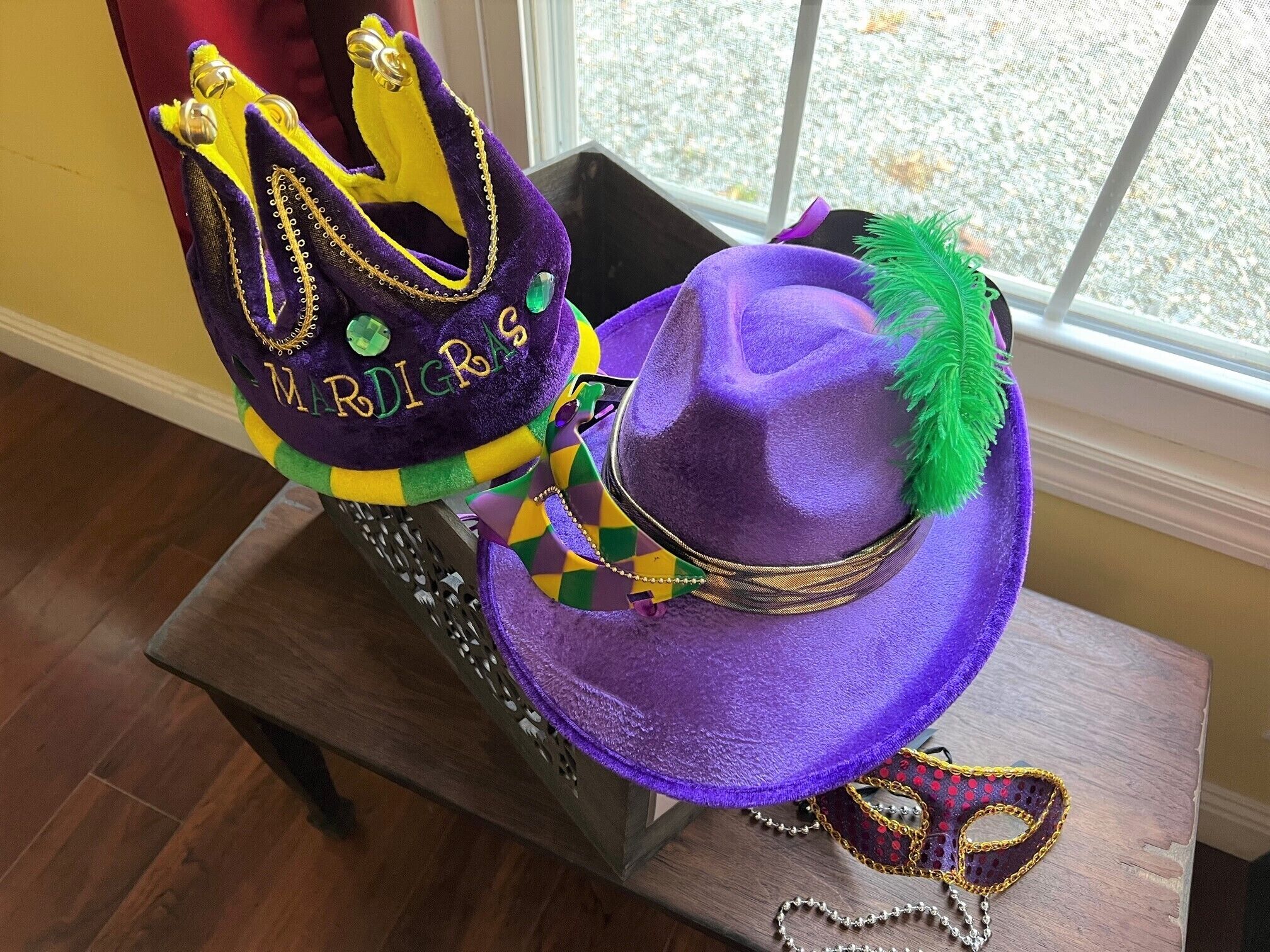 A purple hat with a green feather and a crown with yellow and purple colors.