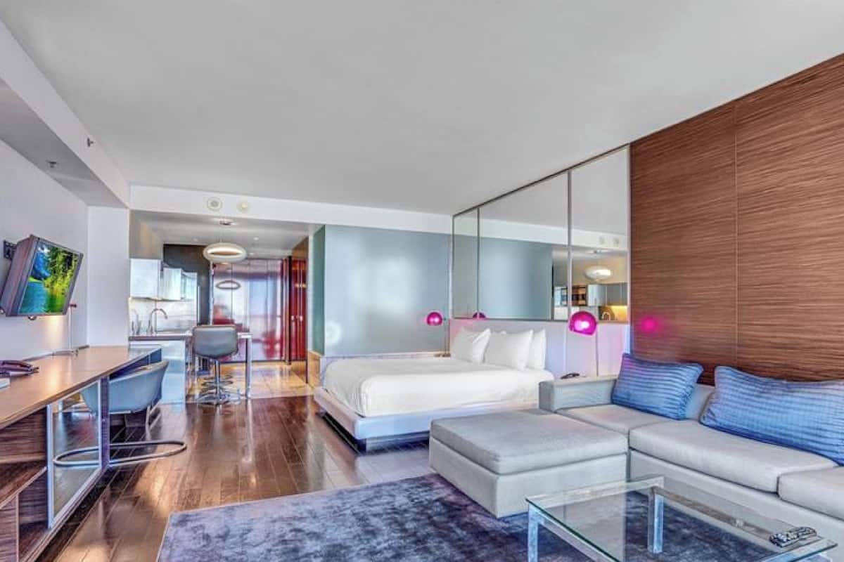 Een moderne hotelkamer met een bed, een bank, een bureau en een grote spiegel.
