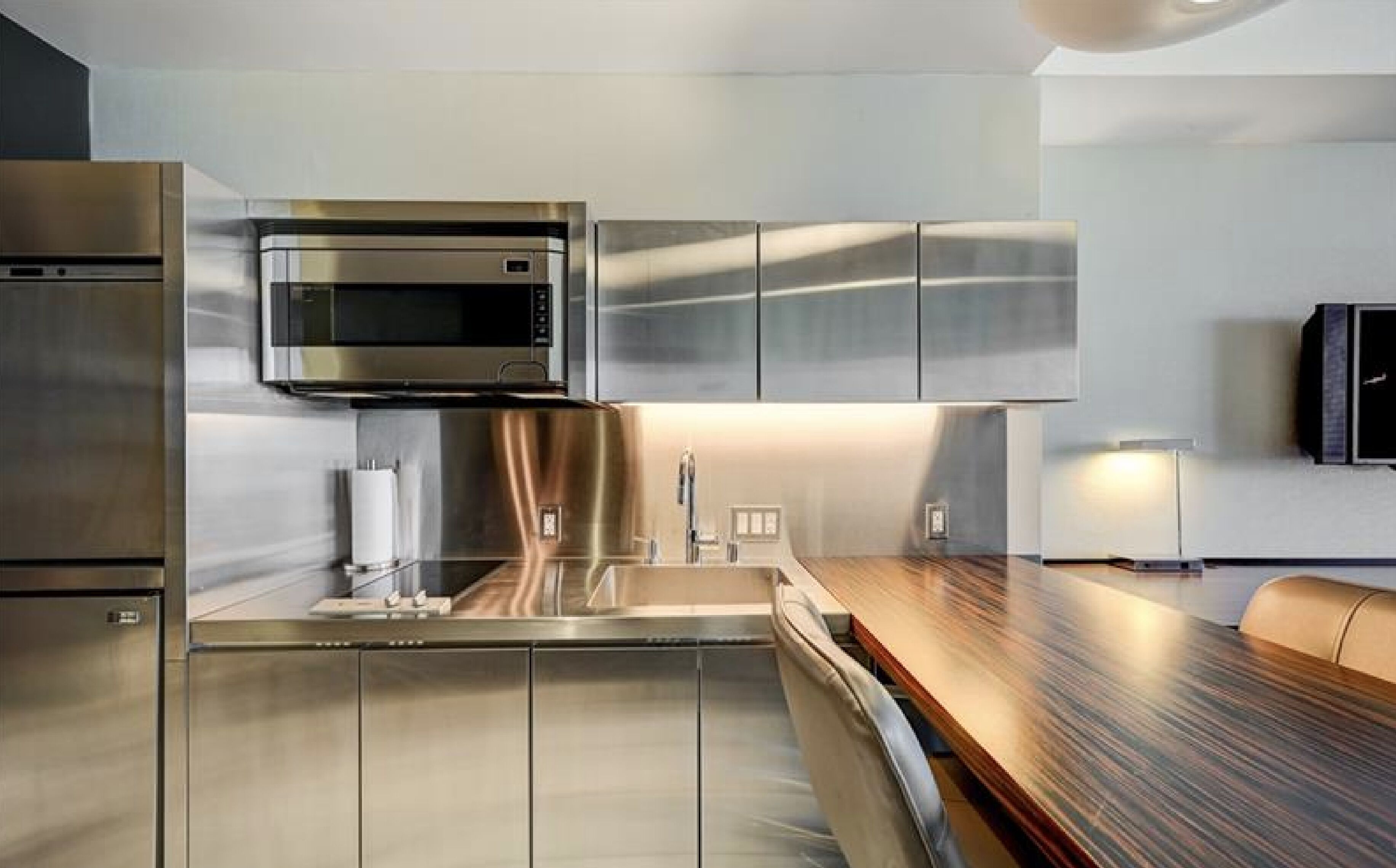 A modern kitchen with stainless steel appliances, a wooden countertop, and a built-in microwave.