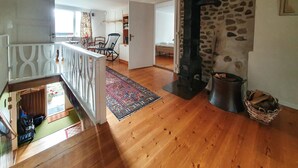 A spacious room with a wooden floor, a stone wall, a fireplace, and a view of a balcony. - Beautiful home in älmhult with kitchen (Älmhult)