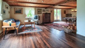 A spacious living room with wooden floors, a sofa, a coffee table, a TV, and a fireplace. - Beautiful home in älmhult with kitchen (Älmhult)
