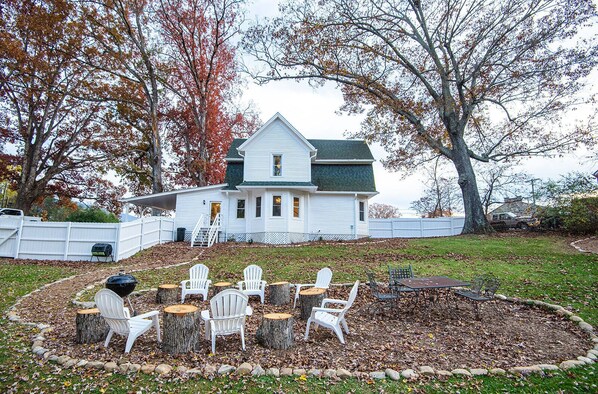 A house with a front yard featuring a wooden deck, a barbecue grill, and outdoor seating with Adirondack chairs. - Relaxing Farmhouse, pet friendly, walk to town (Burnsville)