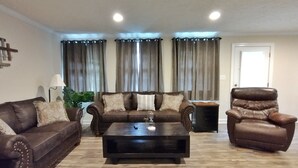 Uma sala de estar com um sofá de couro marrom, uma poltrona combinando e uma mesa de centro de madeira escura.