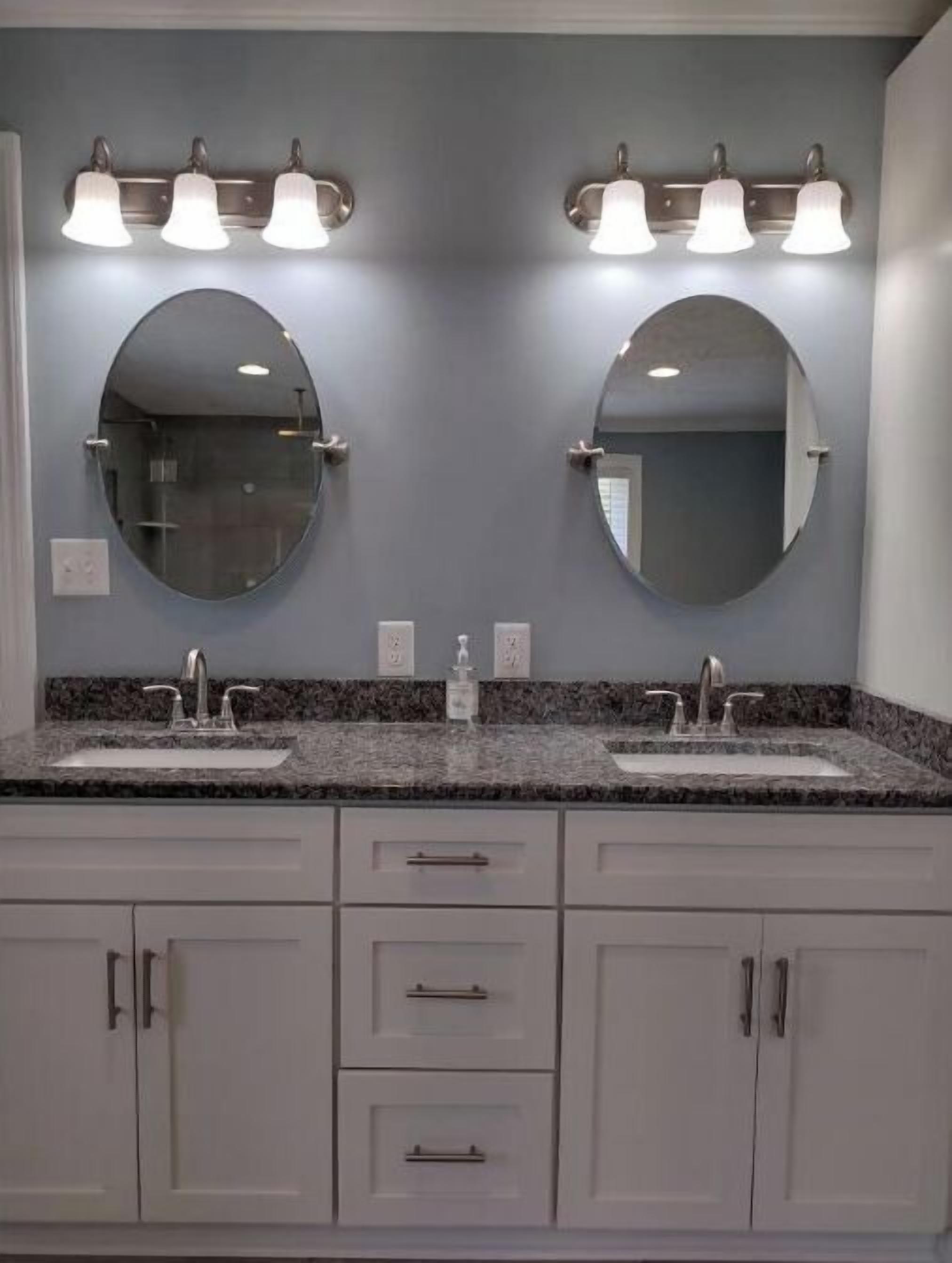 A bathroom with two sinks, a vanity with drawers, and a large mirror above the sinks.