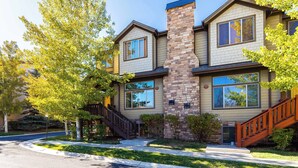 A two-story house with a stone chimney, large windows, and a wooden staircase. - Bear Hollow Heaven Private Hot Tub 4 Bedroom Luxury Condo (Park City)