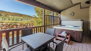 A covered outdoor area with a hot tub, wicker furniture, and a view of a hilly landscape. - Bear Hollow Heaven Private Hot Tub 4 Bedroom Luxury Condo (Park City)
