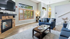 A living room with a stone fireplace, a large flat-screen TV, a blue sofa, and a coffee table. - Bear Hollow Heaven Private Hot Tub 4 Bedroom Luxury Condo (Park City)