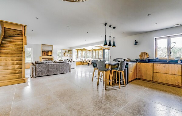 A spacious kitchen with a central island, wooden cabinets, and a large window providing natural light.