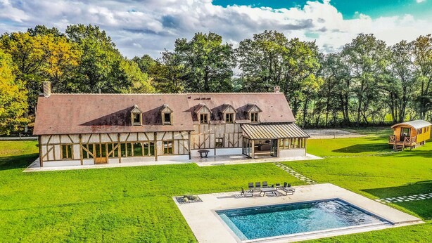 Een groot huis met een zwembad, een overdekte patio en een koetshuijs.