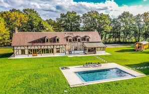 A large house with a swimming pool, a covered patio, and a carriage house.