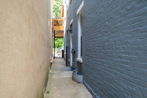 Stylish alleyway between two buildings, featuring a balcony and metal stairway.