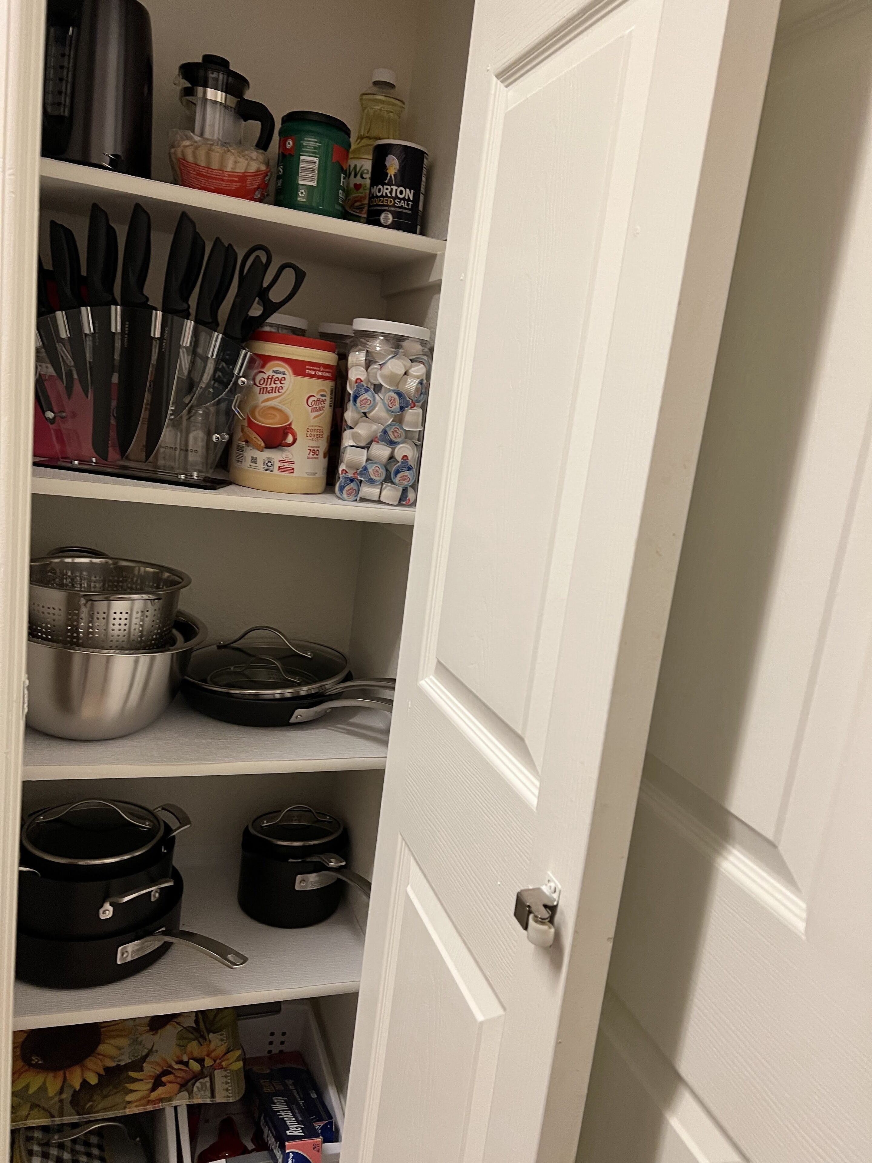 A kitchen pantry with various kitchen utensils, containers, and food items.