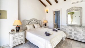 Une chambre d’hôtel avec un grand lit, deux tables de chevet avec des lampes, un miroir et une armoire.