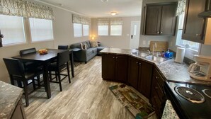 A compact kitchen with a dining area, dark wood cabinets, a central island, and a built-in oven. - Rainbow River Bungalow K (Dunnellon)