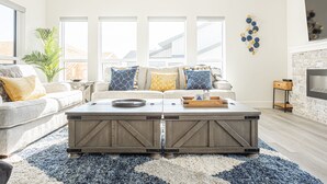 A modern living room with a large sectional sofa, a wooden coffee table, and a fireplace. - Modern Happy Valley Executive TH with Hot Tub (Beaverdell)